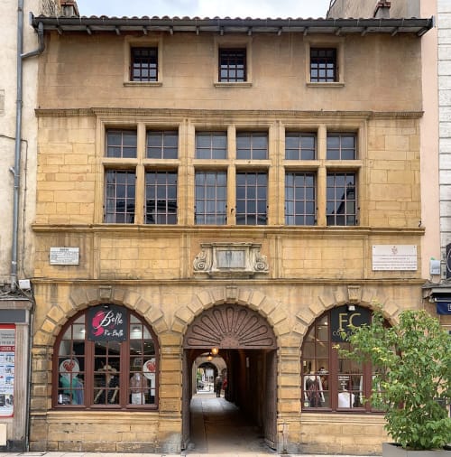 Façade en pierre historique à Blacé, France avec entrées cintrées au rez-de-chaussée et fenêtres à petits carreaux