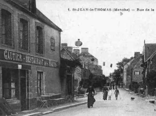 Rue de la Mairie à Saint-Jean-le-Thomas, Manche, France avec bâtiments historiques et café