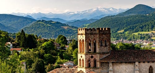 Medieval tower overlooking Montaut valley with snow-capped mountains and green hills in background