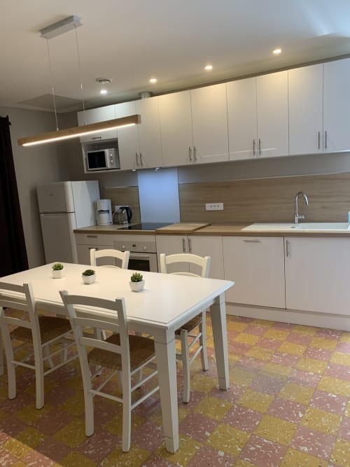 Modern open-plan kitchen and dining area in Cottage L'Arbousier at Gites Mas D'en Ratéro, Thuir, with white cabinetry and