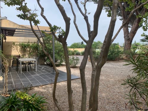 Garden terrace at Mas D'en Ratéro cottage in Thuir with mature trees, patio seating, and countryside views