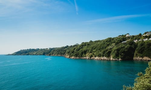 Vue sur la baie turquoise avec falaises verdoyantes à L'Abri Des Vents à Saint-Jean-le-Thomas, France