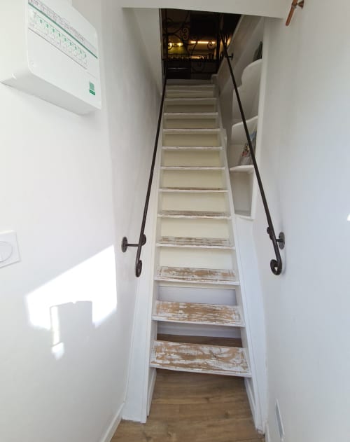 Escalier étroit en bois avec rampes métalliques noires menant au Studio du Petit Nid d'Aigle à Giverny