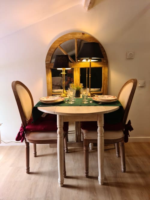 Élégant aménagement de salle à manger au Studio du Petit Nid d'Aigle à Giverny : table ronde, chaises en bois et vue voûtée sur le jardin