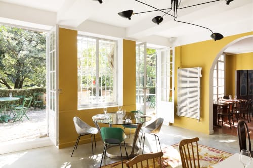 Salle à manger lumineuse aux murs jaunes, table ronde et vue sur le jardin au Mas De Lafeuillade B&B près de Montpellier
