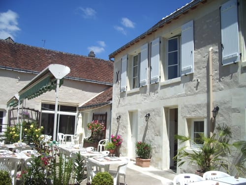 Château de Ré B&B courtyard in Le Petit Pressigny with whitewashed buildings, flowering plants, and outdoor dining area