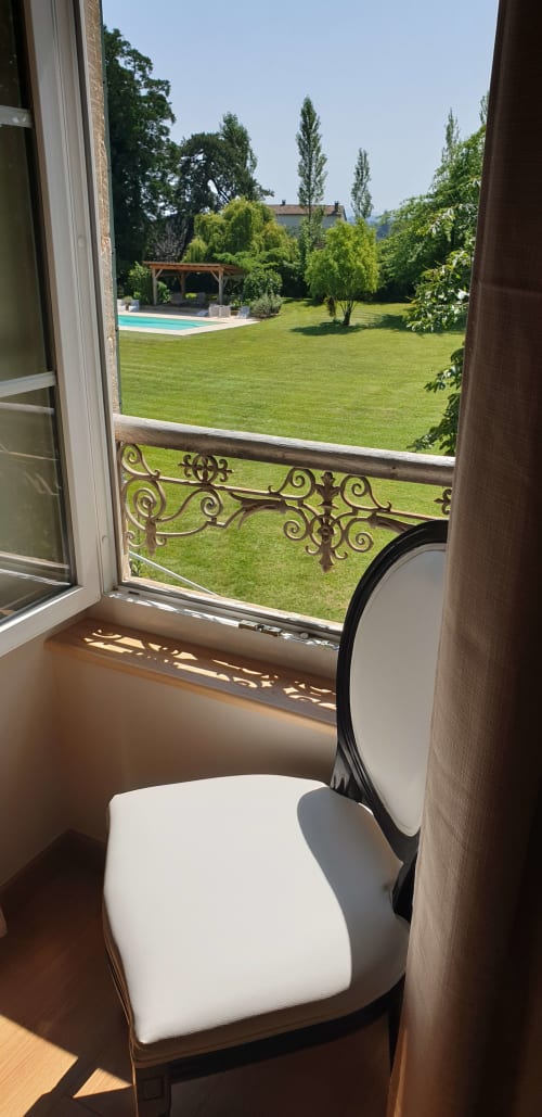 Vue du jardin depuis la chambre du Château de Grandmont avec pelouse soignée, pavillon de la piscine et peupliers à Blacé
