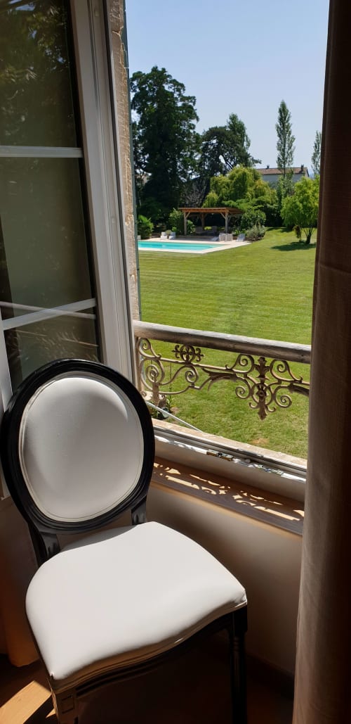 Chaise blanche près de la fenêtre donnant sur la piscine du jardin du Château de Grandmont, Blacé