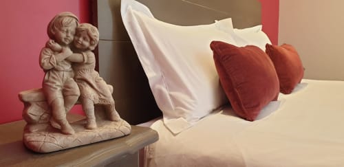Chambre Energie du Château de Grandmont avec statue de chérubin, oreillers blancs et coussins rouges en forme de cœur sur le lit