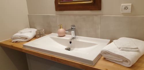 Lavabo moderne du Château de Grandmont B&B avec serviettes blanches, distributeur de savon rose et meuble vasque en bois à Blacé