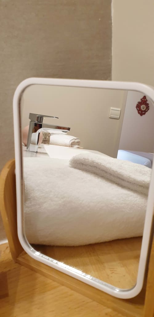 Miroir de salle de bains reflétant les serviettes et le lavabo de la chambre d'hôtel du Château de Grandmont, Blacé