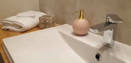 Lavabo moderne au Château de Grandmont B&B avec distributeur de savon rose, robinet chromé et serviettes blanches
