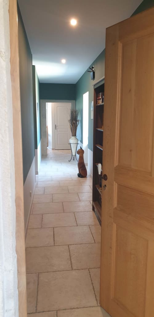 Couloir contemporain du cottage Château de Grandmont avec murs bleu-vert, portes en bois et carrelage