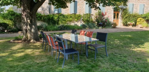 Installation de repas en plein air sous un grand arbre au Château de Grandmont, Blacé, avec des chaises colorées et bâtiment en pierre