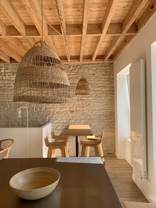 Cuisine de cottage moderne aux Filles du Bord de Mer avec luminaires en osier, poutres apparentes, murs en pierre, espace repas