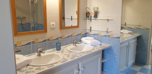 Salle de bains spacieuse au cottage Château de Grandmont avec doubles vasques, accents carrelage bleu et vue sur jardin à Blacé