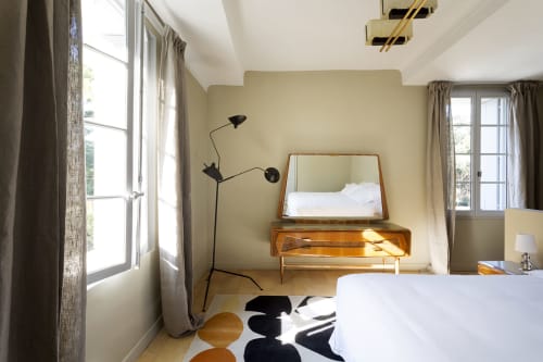 Modern bedroom at Mas De Lafeuillade B&B in Montpellier with vintage furnishings, large windows, and contemporary black lamp.