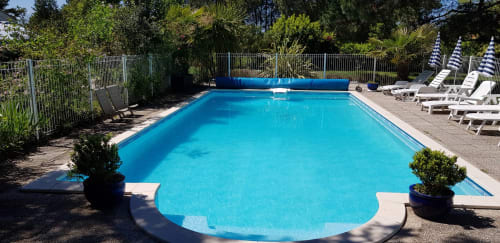 Piscina azzurro cristallino presso Le Manoir Lacustre B&B a Queyrac con lettini e lussureggiante verde