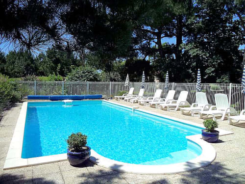 Piscina de resort al Manoir Lacustre a Queyrac amb gandules i tancament blanc envoltat d'arbres