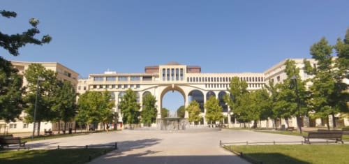 Montpellier's historic archway plaza with classical architecture and green trees
