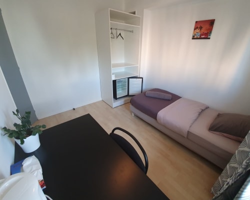 Chambre compacte au NancyRoom B&B à Vandoeuvre-les-Nancy avec lit simple, penderie, bureau et affiche vue sur la ville