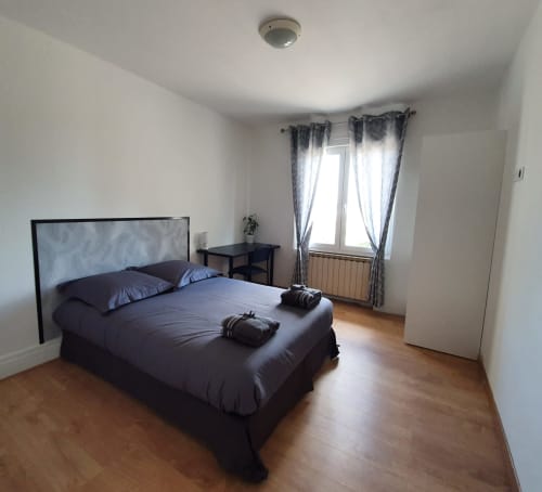 Chambre moderne à NancyRoom à Vandœuvre-lès-Nancy avec lit queen-size, literie noire, parquet et vue sur la ville