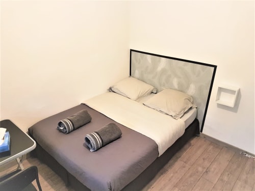 Lit double moderne avec parure beige et serviettes roulées à la NancyRoom BnB à Vandoeuvre-les-Nancy