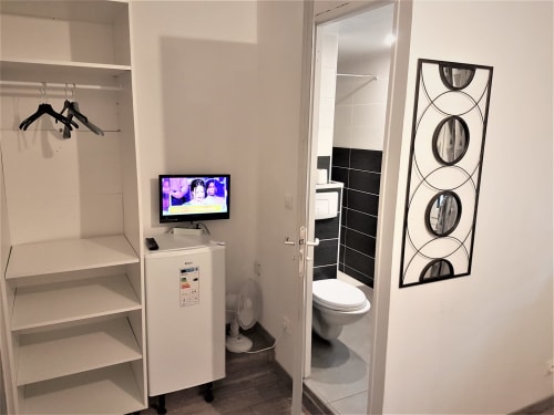 Chambre moderne de la NancyRoom B&B à Vandœuvre-lès-Nancy avec placard, télévision et salle de bains aux accents de carrelage noir