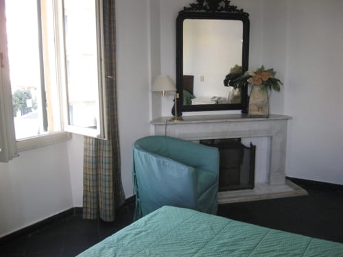 Zimmer des Hotel Beau Rivage mit Kamin, türkisfarbener Bettwäsche, Schreibtisch, Spiegel und Stadtblick in Alassio