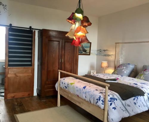 Chambre lumineuse avec lits en bois, lampe suspendue colorée et vue sur le jardin à L'Ermitage B&B