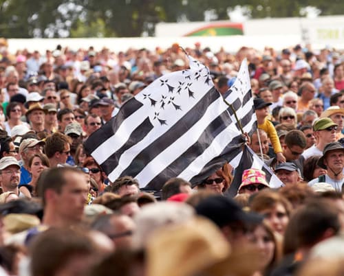 Breton flag waving at outdoor event in Finistère, France with large crowd gathered