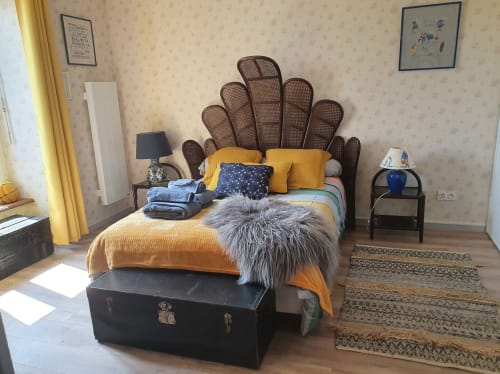 Chambre aux Forges Du Lou avec tête de lit en rotin, literie jaune et malle vintage au pied du lit