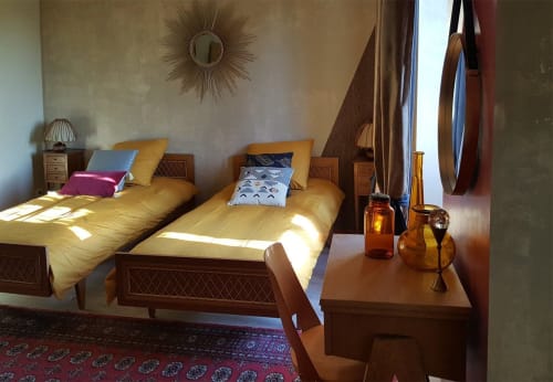 Chambre double aux Forges Du Lou avec lits en bois, parure jaune et mobilier d'époque à Jugon-les-Lacs, France.