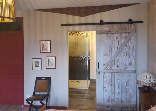Chambre moderne aux Forges du Lou avec porte grange coulissante, œuvres d'art encadrées et mobilier contemporain