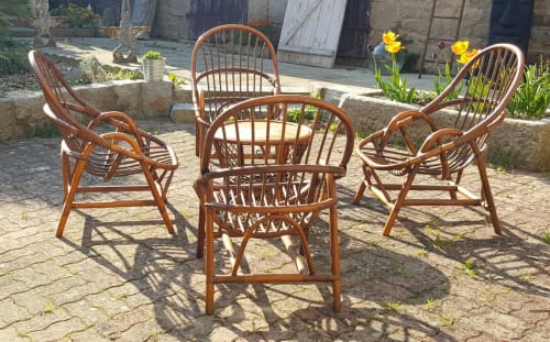 Trois chaises en rotin sur la terrasse des Forges Du Lou à Jugon-les-Lacs, fleurs jaunes et murs en pierre