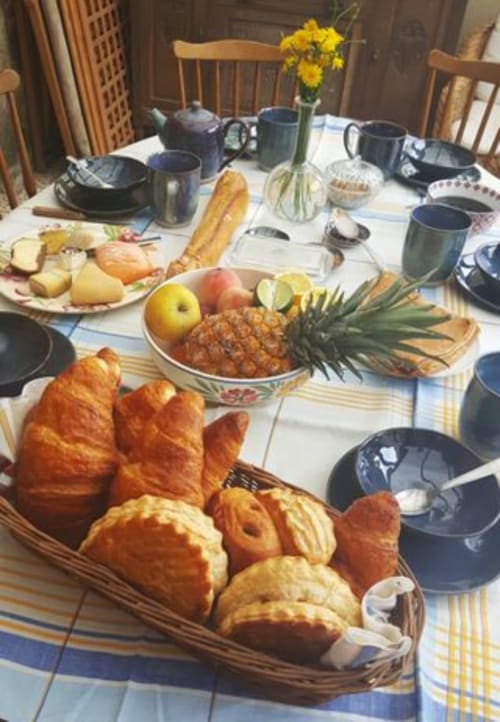 Petit-déjeuner aux Forges Du Lou avec viennoiseries, pain frais, fruits et vaisselle bleue à Jugon-les-Lacs