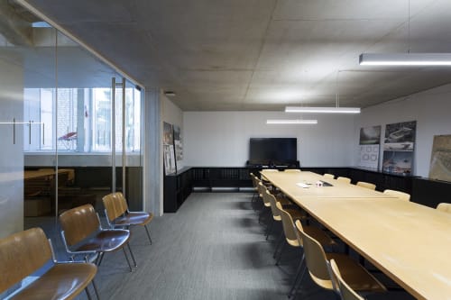 Modern conference room at Mas De Lafeuillade in Montpellier with long wooden table, leather chairs, and glass partitions