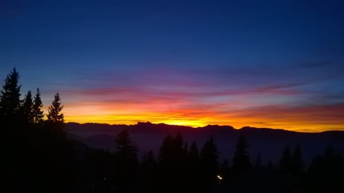 Coucher de soleil sur la vallée de montagne avec des sapins en silhouette à L'étape Du Fanfoué, Chamrousse