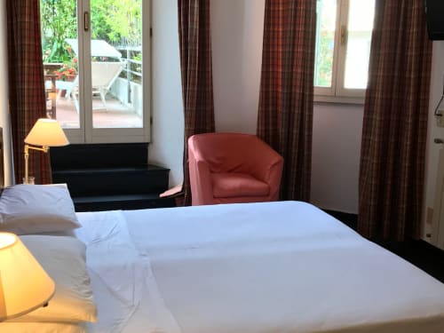 Zimmer des Hotel Beau Rivage in Alassio mit Doppelbett, rotem Sessel und Terrassenzugang