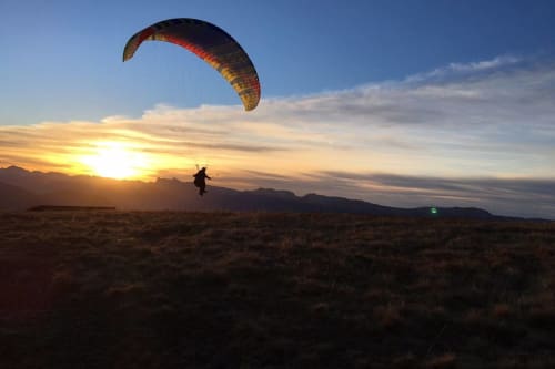 Paraglider soaring at sunset over Chamrousse desert landscape near L'étape Du Fanfoué