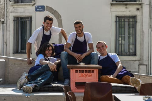 Four smiling staff members at Mas De Lafeuillade BnB in Montpellier, posing outdoors on a sunny street