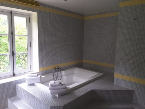 Salle de bains luxueuse du Château de Ré avec baignoire encastrée, carrelage mosaïque et vue sur le jardin