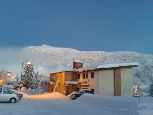 L'étape Du Fanfoué BnB à Chamrousse enneigée au crépuscule avec des pics montagneux couverts de neige