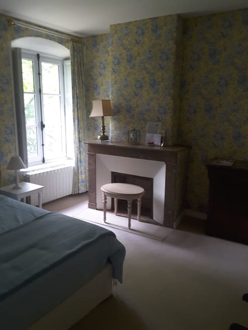Chambre Dauphine du Château de Ré avec papier peint fleuri, cheminée, coiffeuse et vue sur le jardin
