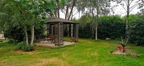 Garden gazebo with seating at Aux Prés Du Berry B&B in Chavin, France surrounded by trees and lawn