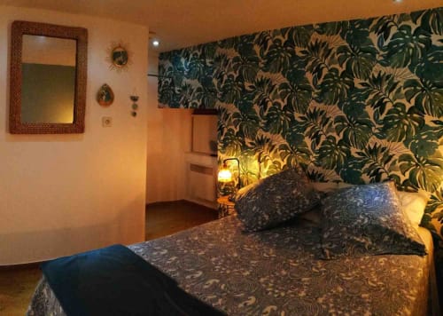 Cozy bedroom at Aux Prés Du Berry B&B with tropical wallpaper, patterned bedding, and warm lighting in Chavin, France