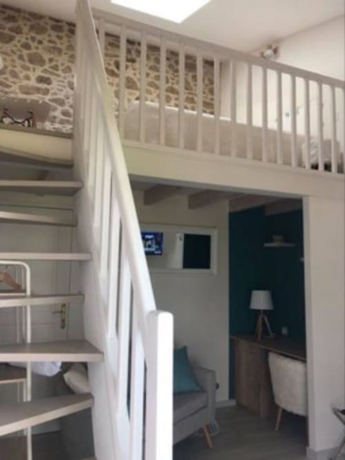 Suite du Meunier mezzanine bedroom with white railings and stone wall at Logis De La Bénétière, Treize-Vents