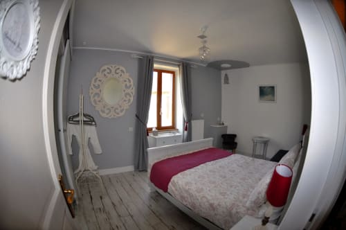Cozy bedroom at Aux Prés Du Berry B&B in Chavin with white bed, burgundy accents, and ornate wall decor