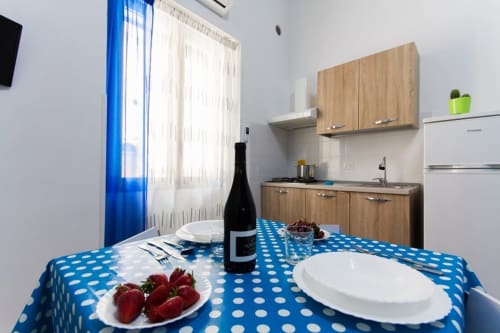 Studio Blu kitchen-dining area at Casa Vacanze Del Golfo with blue polka dot tablecloth, wine bottle, fresh strawberries, and