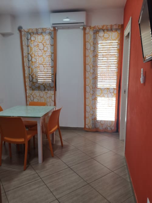 Modern dining area in Apartment Orange at Casa Vacanze Del Golfo with table, orange chairs, air conditioning, and patterned